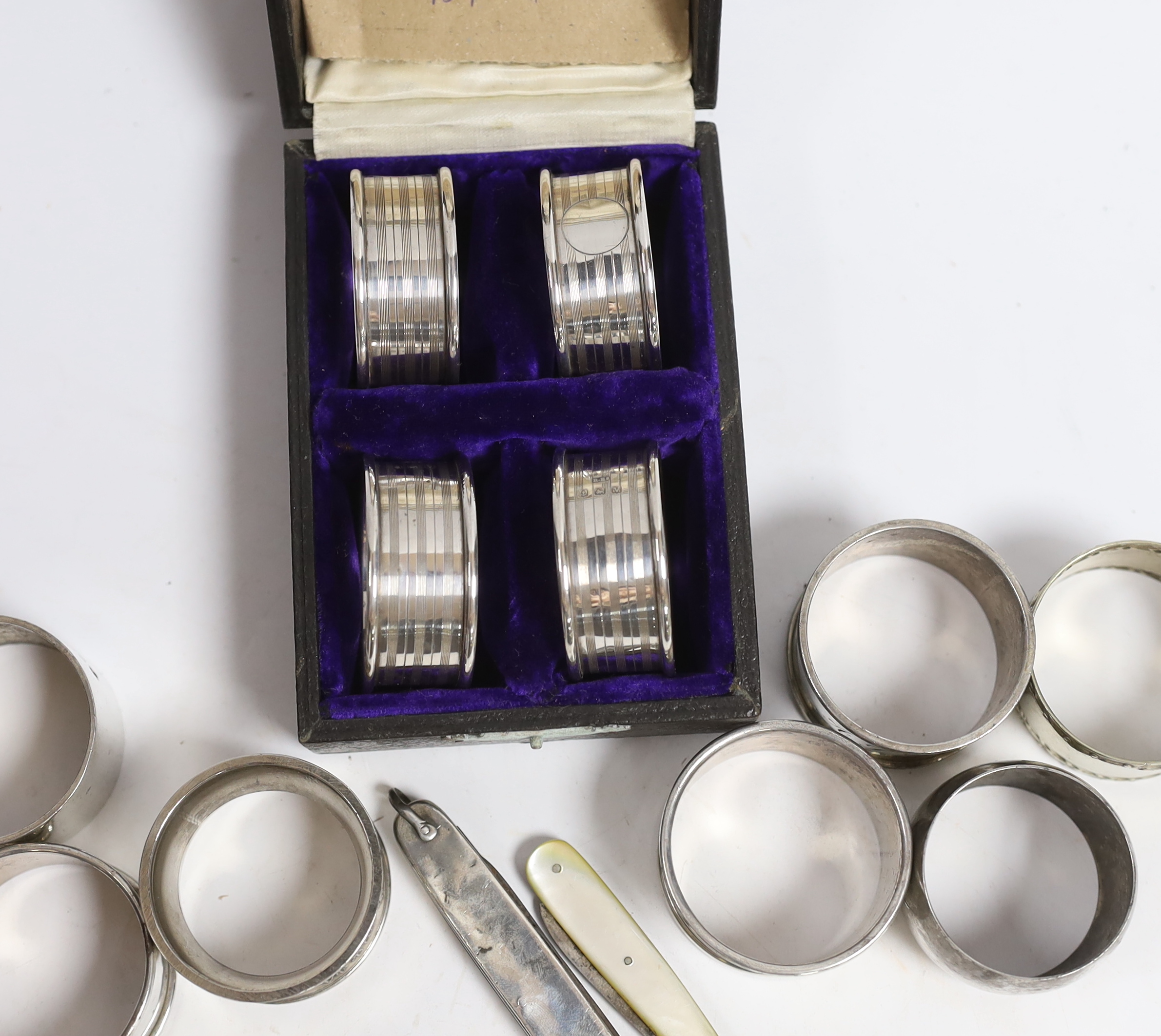 A cased set of four George V silver napkin rings, Rolason Brothers, Birmingham, 1920, together with five other assorted silver napkin rings, three plated napkin rings, two mother of pearl mounted fruit knives and a silve